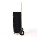 A side view of the black Joyrolla cart, highlighting its tall handle and sleek design. The cart features a long, ergonomic handle that reaches above waist height, allowing for comfortable maneuvering and effortless pushing or pulling. Its sleek design is characterized by clean lines and a streamlined silhouette. This black Joyrolla cart combines functionality and style, offering a practical solution for transporting items with ease while exuding a modern and sophisticated aesthetic.